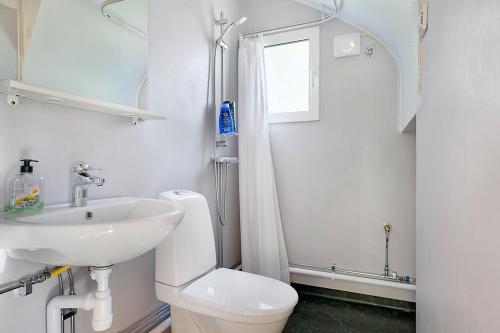 een witte badkamer met een wastafel en een toilet bij Guestly Homes - 3BR Lakeview House in Piteå