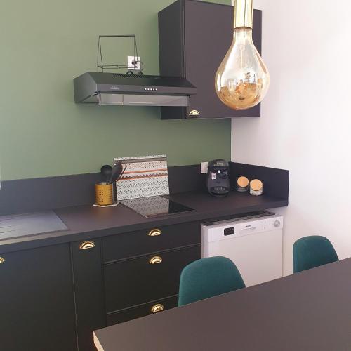 a kitchen with black cabinets and a counter with blue chairs at Gîtes Ô Café "Appartement 2 pièces" in Lazer