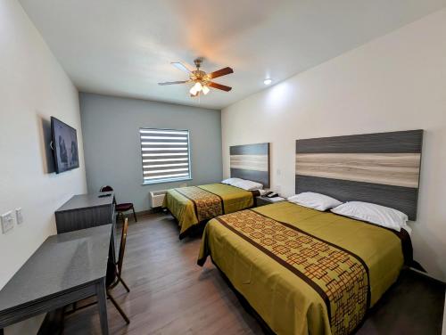 a hotel room with two beds and a ceiling fan at Texas Bungalows Hotel and Hotel Que in Pflugerville