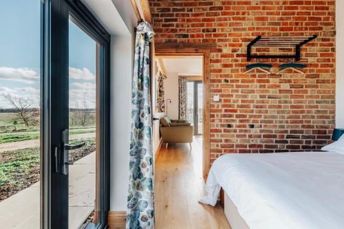 a brick walled bedroom with a bed and a window at The Linhay in Peterborough