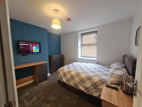 a bedroom with a bed and a tv on the wall at Cozy 6 Bedroom HMO in Eston