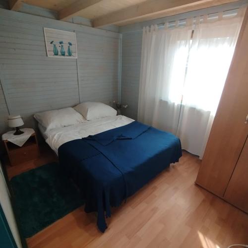 a bedroom with a bed with a blue blanket and a window at Ośrodek Azyl Mironice in Kłodawa