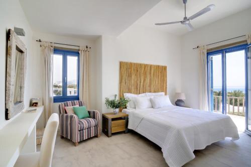 a white bedroom with a bed and a chair at VILLA SOROS in Antiparos