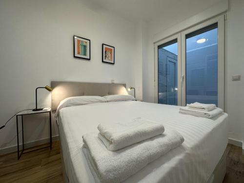 Un dormitorio con una cama blanca con toallas. en Valdeolivas Suites, en Valencia