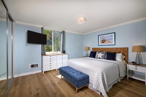 a bedroom with blue walls and a bed and a tv at Seaside Cottage in Oceanside