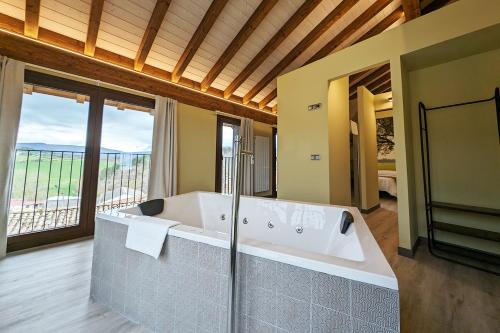 Habitación con ventanas y baño grande con bañera. en Hotel Rural Milaleku, 