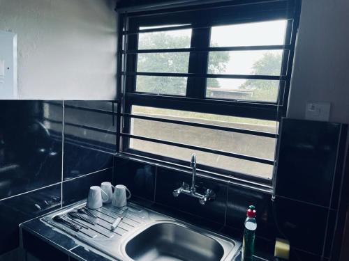 uma cozinha com um lavatório e uma janela em Rocksie Apartments em Maun
