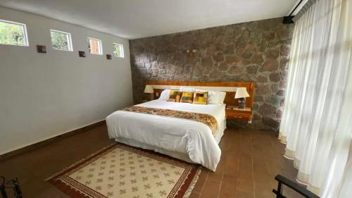a bedroom with a large bed and a stone wall at Cabin Manzana Nature Retreat with amenities in Zitácuaro