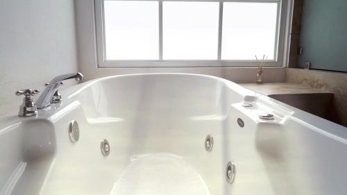 a white bath tub in a bathroom with a window at Cabin Manzana Nature Retreat with amenities in Zitácuaro