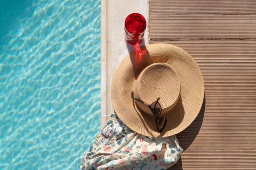 un sombrero de paja sentado junto a una piscina en Olea Serenity Villa en Loutráki