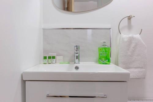 a bathroom sink with a green bottle on it at Wilshere House in Kirby Muxloe