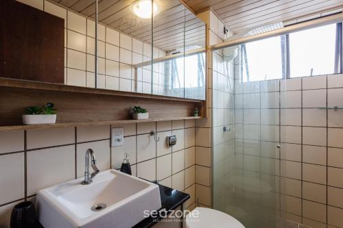 Un baño con lavabo y ducha de cristal. en Apto tranquilo a 3min da praia Canasvieiras FML202, en Florianópolis