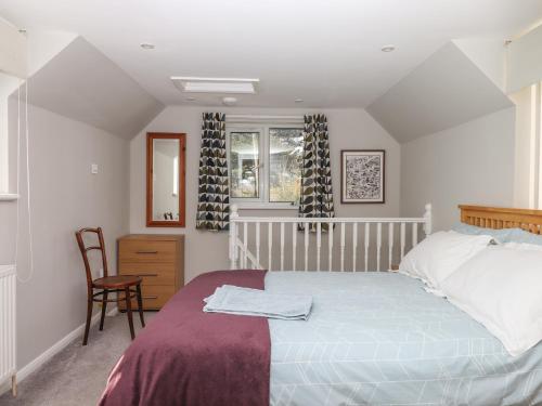 a bedroom with a bed and a chair and a window at Wisteria Cottage in Exmouth