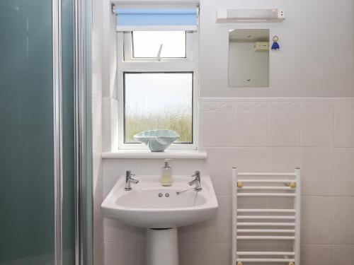 a white bathroom with a sink and a window at Wisteria Cottage in Exmouth
