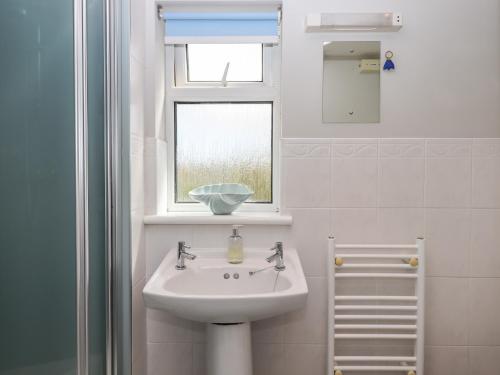 un bagno bianco con un lavandino e una finestra di Wisteria Cottage a Exmouth