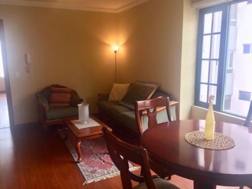 uma sala de estar com uma mesa e um sofá em Departamento Amoblado em Quito