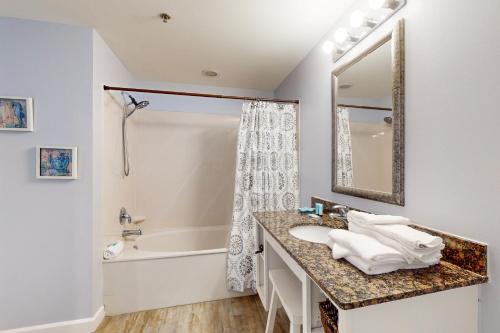 a bathroom with a sink and a tub and a mirror at Splash Resort 1901W Suite A Studio in Panama City Beach