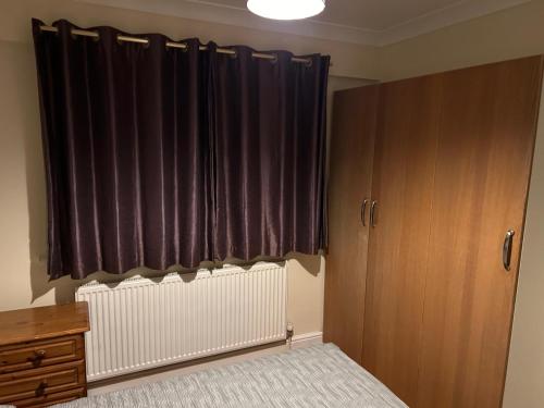 a bedroom with a radiator and a window with curtains at Sw17 7ls in London
