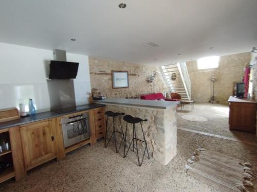 une cuisine avec un comptoir et des tabourets dans une pièce dans l'établissement Joli hébergement de caractère en bord de rivière, à Saint-Vincent-sur-lʼIsle