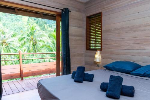 - une chambre avec un lit doté d'oreillers bleus et un balcon dans l'établissement Villa Terai 2BR Legends Moorea wPool, à Papetoai