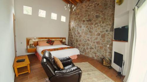 a bedroom with a bed and a chair and a tv at Cabin Nispero Nature Retreat with amenities in Zitácuaro