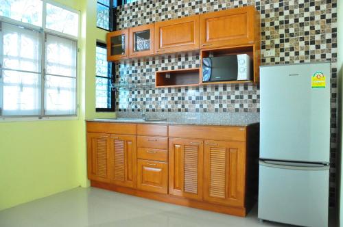 a kitchen with wooden cabinets and a white refrigerator at Mekong Tarawadee Villa in Tha Bo