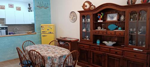 a dining room with a table and a kitchen at SE LO SENTI LO SAI in Triscina