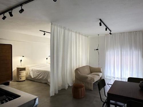 een witte slaapkamer met een bed en een stoel bij Mini loft in Reggio Emilia