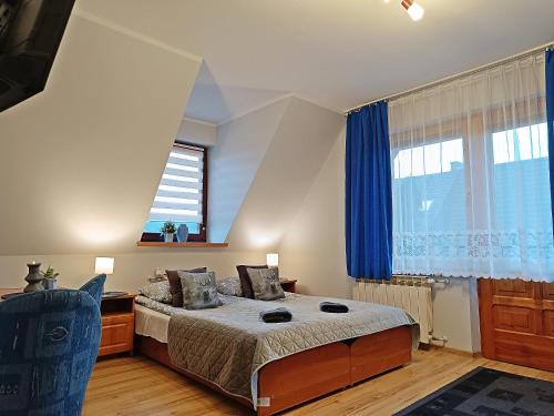 1 dormitorio con 1 cama con cortinas azules y ventana en Willa Żółta Turnicka, en Zakopane