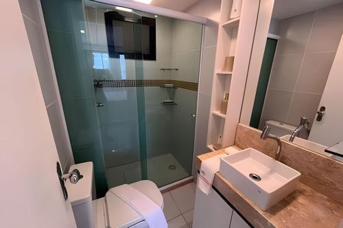 uma casa de banho com uma cabina de duche em vidro e um lavatório. em Hosts BR - Flat frente mar c/ cozinha em Fortaleza