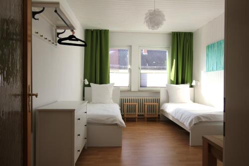 ハノーファーにあるCentrally located 2-room apartmentのベッドルーム(ベッド2台、緑のカーテン付)
