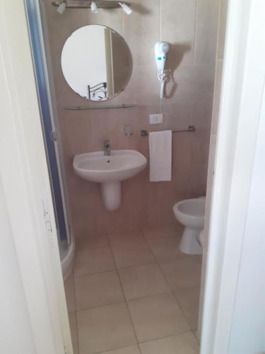 a bathroom with a sink and a mirror and a toilet at Trulli Nonna Grazia -miramonti in Cisternino