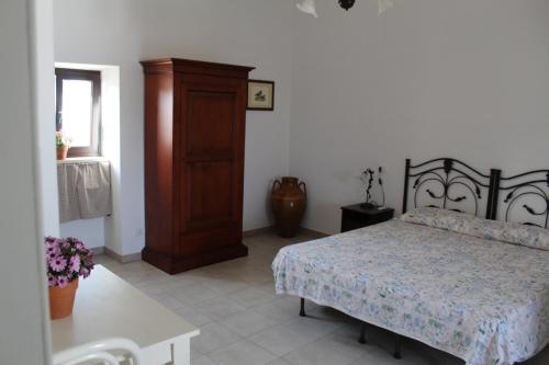 a bedroom with a bed and a wooden cabinet at Trulli Nonna Grazia -miramonti in Cisternino
