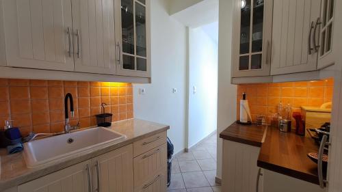 a kitchen with white cabinets and a white sink at Tomis Sea View Apartment in Piraeus