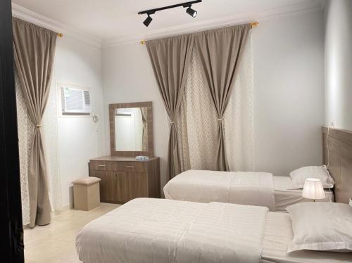 Habitación de hotel con 2 camas y espejo en نايتس للوحدات المفروشة, en Tabuk