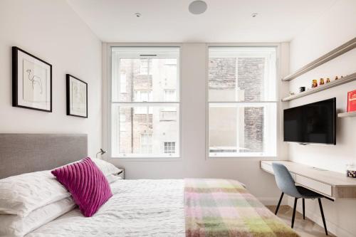 a bedroom with a bed and a desk and windows at Modern Apartment & Rooms at Charing Cross in London
