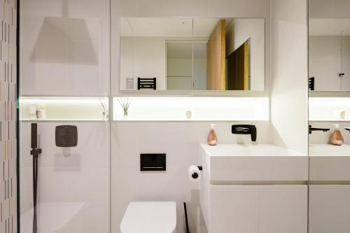 La salle de bains blanche est pourvue de toilettes et d'un miroir. dans l'établissement Modern Apartment & Rooms at Charing Cross, à Londres