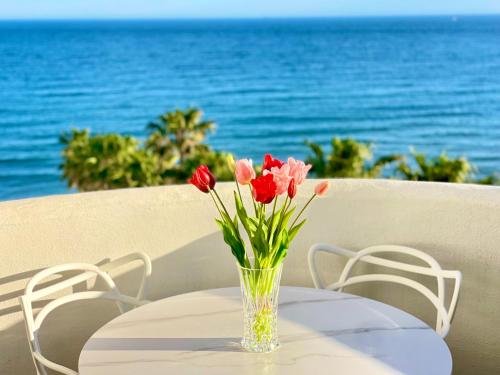 a vase of flowers sitting on a table with the ocean at Algaida, beach apartment in Mijas Costa