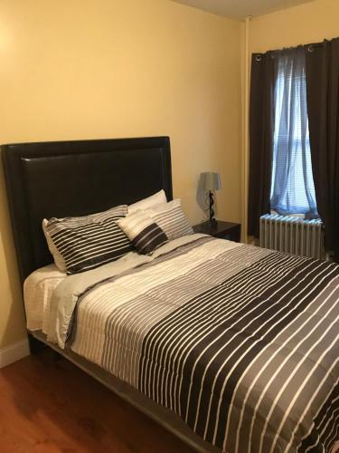 een bed met gestreepte lakens en kussens in een slaapkamer bij Alykas Properties in Brooklyn
