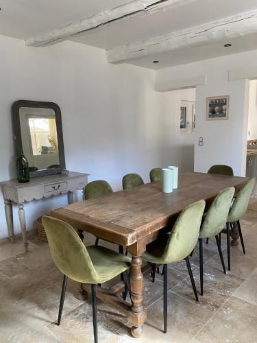 a dining room table with green chairs and a mirror at Chez prune in Rasteau