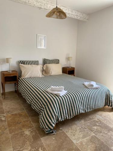 a bedroom with a large bed with a striped blanket at Chez prune in Rasteau