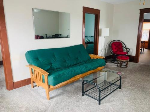 a green couch in a living room with a glass table at 2BR Erie Flat Remote Work Family-Friendly in Erie