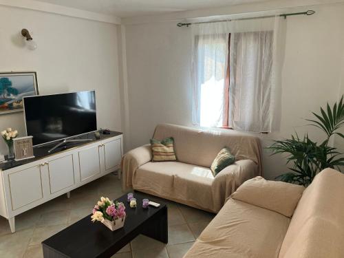 ein Wohnzimmer mit einem Sofa und einem Flachbild-TV in der Unterkunft Villa Grecale in Cala Liberotto