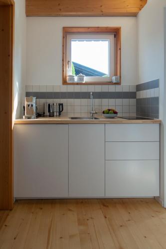 a kitchen with white cabinets and a window at Rückzugsort mitten im Paradies in Feldafing