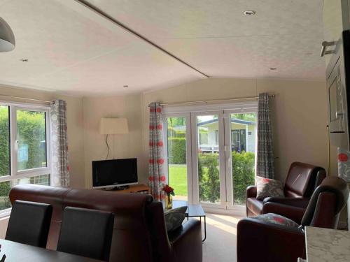 a living room with couches and a tv and windows at Luxury spacious house with two bathrooms at park with swimming pools, restaurant, bowling, massage & wellness in Voorthuizen
