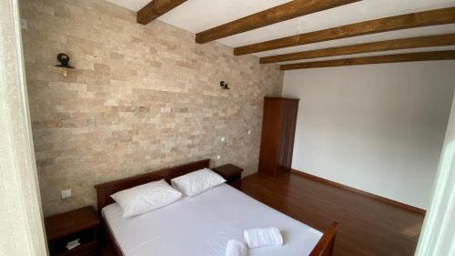 a bedroom with a white bed and a brick wall at Medo in Ulcinj
