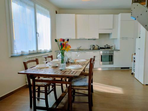 a kitchen with a wooden table with chairs and flowers on it at Villa Livia - L'Opera Group in La Spezia