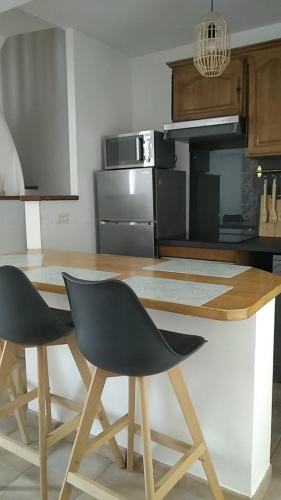 une cuisine avec une table en bois et deux chaises dans l'établissement Le triplex Saint Aphrodise, terrasse au calme et parking gratuit, à Béziers