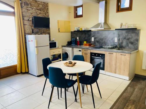 une cuisine avec une table, des chaises et un réfrigérateur dans l'établissement La grange à Papillon, à Saint-Ferriol