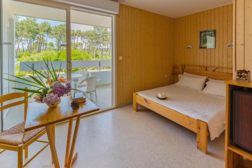 Azureva Lacanau في لاكانو: غرفة نوم بسرير وطاولة وبلكونة